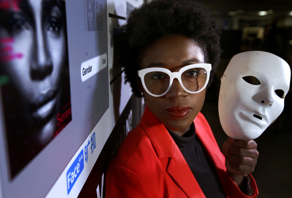 Joy Buolamwini holding a white mask